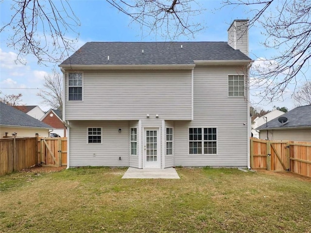 back of property with a gate, a yard, and a chimney