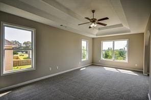 spare room with dark carpet, a raised ceiling, and ceiling fan