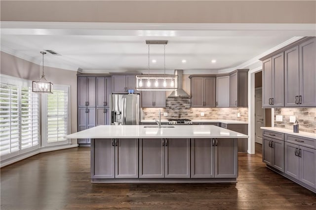 kitchen with visible vents, wall chimney range hood, stainless steel fridge with ice dispenser, light countertops, and a kitchen island with sink