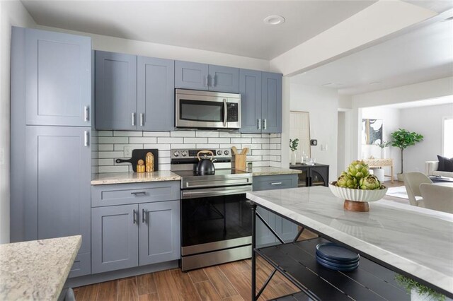 1258 Campbellton Rd SW, Atlanta, GA 30310 - kitchen featuring appliances with stainless steel finishes, backsplash, dark wood-type flooring, light stone countertops, and open floor plan