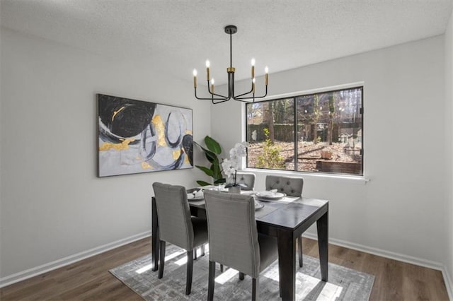 dining space with wood finished floors, a textured ceiling, baseboards, and an inviting chandelier