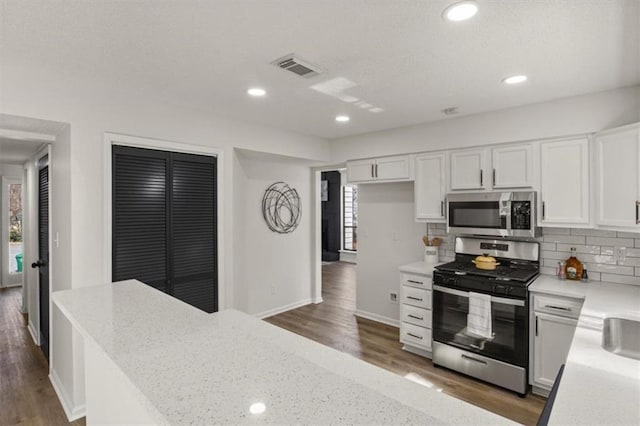 kitchen featuring white cabinets, dark wood finished floors, stainless steel appliances, and decorative backsplash