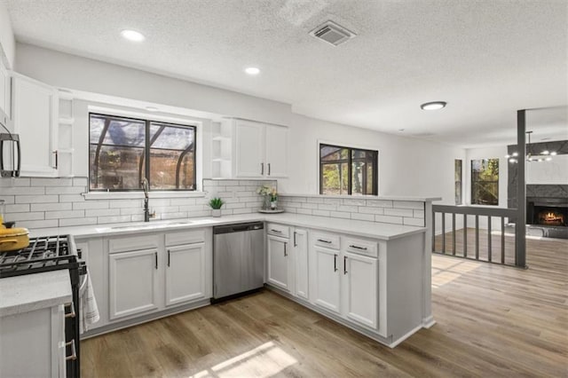 kitchen featuring a peninsula, visible vents, open shelves, and stainless steel dishwasher