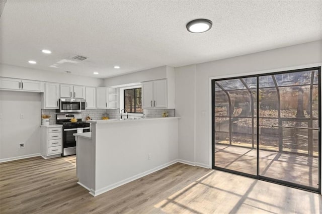 kitchen featuring stainless steel appliances, visible vents, white cabinets, light wood-type flooring, and open shelves