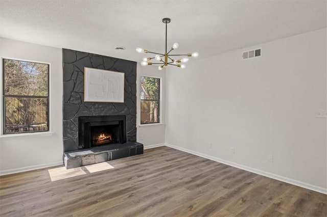 unfurnished living room with a large fireplace, wood finished floors, visible vents, and baseboards