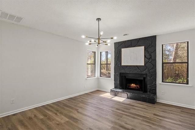 unfurnished living room featuring a fireplace, visible vents, a wealth of natural light, and wood finished floors