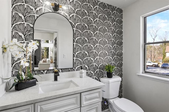 bathroom featuring vanity, toilet, and wallpapered walls