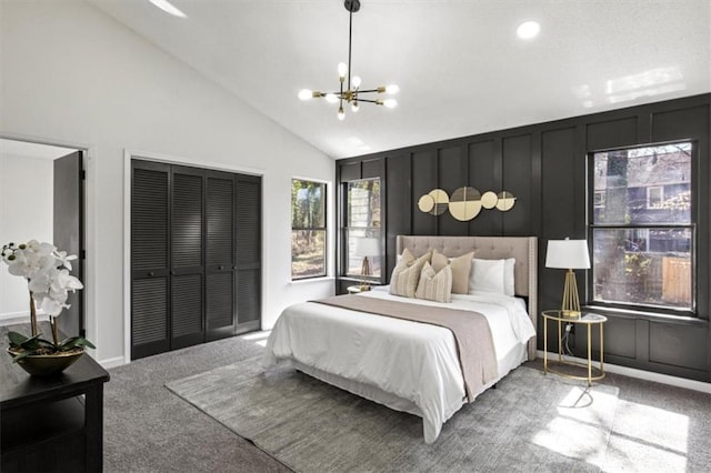 carpeted bedroom featuring a chandelier, vaulted ceiling, a closet, and a decorative wall