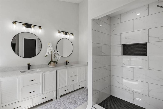 full bath featuring double vanity, a tile shower, and a sink