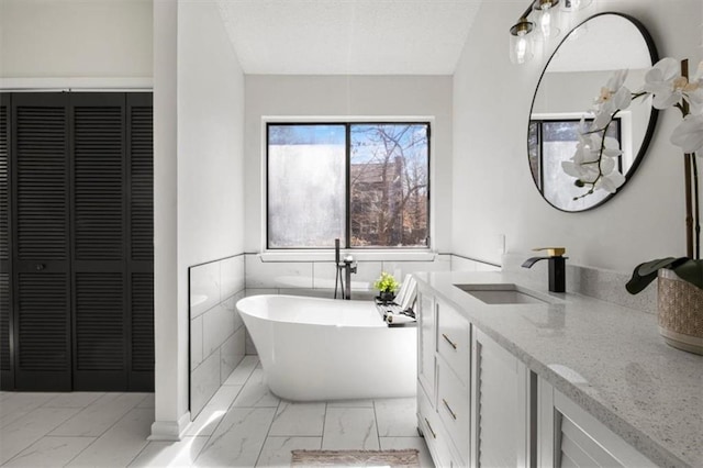 full bathroom featuring a freestanding bath, marble finish floor, a closet, and vanity