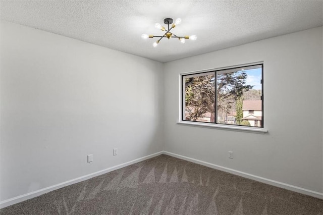 carpeted spare room with baseboards, a textured ceiling, and a notable chandelier