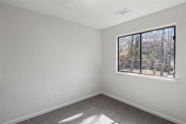 empty room with carpet floors, baseboards, visible vents, and a textured ceiling