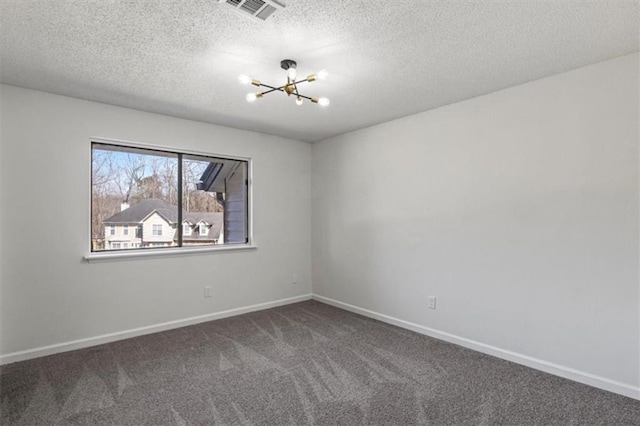 spare room with carpet floors, a notable chandelier, visible vents, a textured ceiling, and baseboards