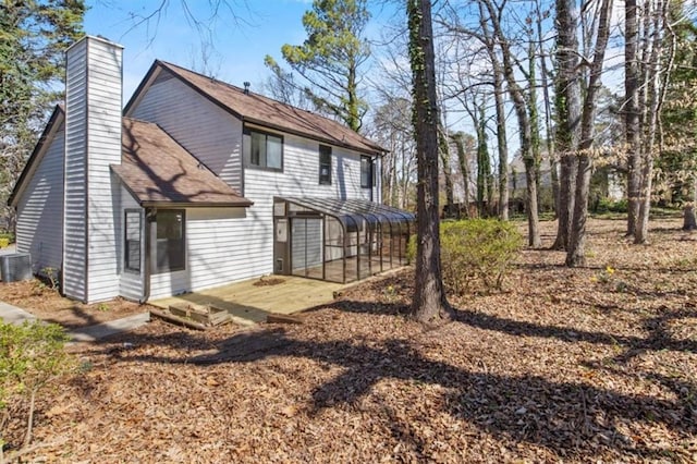 rear view of property with dirt driveway, a deck, a chimney, and central air condition unit