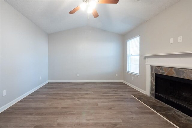 unfurnished living room featuring lofted ceiling, ceiling fan, a fireplace, and wood-type flooring