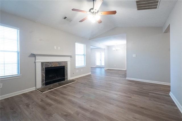 unfurnished living room featuring ceiling fan with notable chandelier, vaulted ceiling, hardwood / wood-style floors, and a wealth of natural light