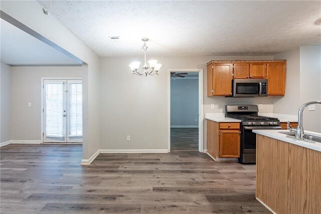 kitchen featuring appliances with stainless steel finishes, dark wood-type flooring, pendant lighting, and sink