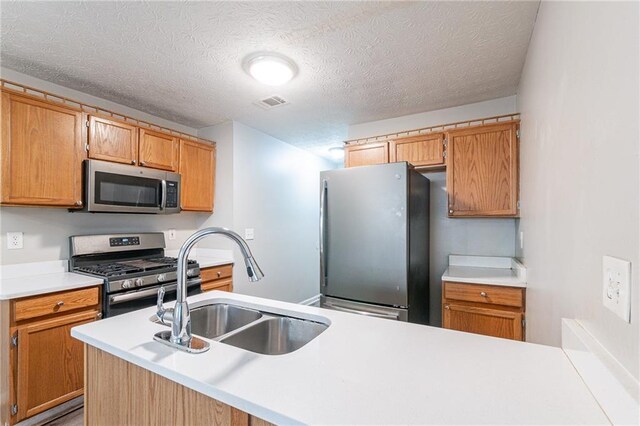 kitchen with stainless steel appliances, sink, and a textured ceiling