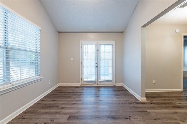 spare room with french doors, dark hardwood / wood-style flooring, vaulted ceiling, and a wealth of natural light