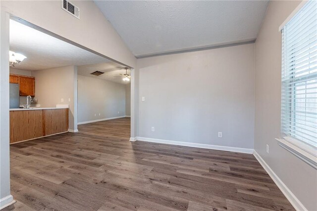 interior space featuring sink, vaulted ceiling, a textured ceiling, dark hardwood / wood-style flooring, and ceiling fan with notable chandelier