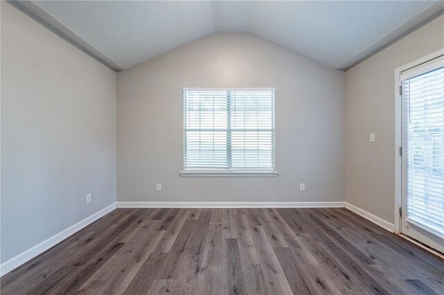 spare room featuring lofted ceiling and dark hardwood / wood-style floors