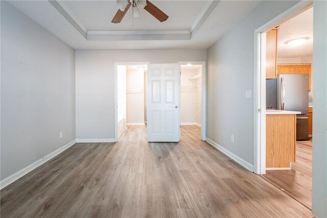 empty room featuring hardwood / wood-style flooring, ornamental molding, a raised ceiling, and ceiling fan