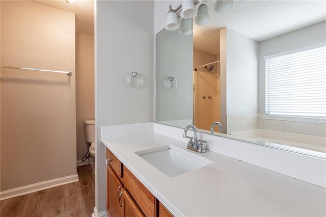 bathroom featuring hardwood / wood-style floors, a bathtub, vanity, a textured ceiling, and toilet