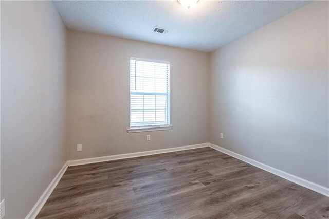 empty room featuring dark wood-type flooring and a textured ceiling