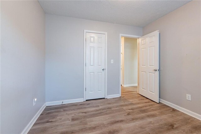 unfurnished bedroom with a textured ceiling and light wood-type flooring