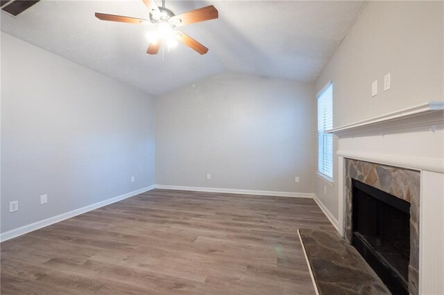 unfurnished living room with lofted ceiling, a stone fireplace, ceiling fan, and hardwood / wood-style flooring