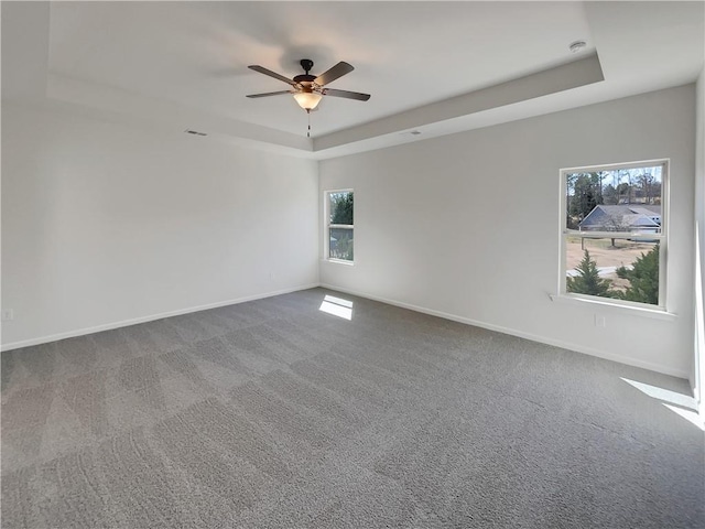 carpeted spare room with baseboards, a raised ceiling, visible vents, and a ceiling fan