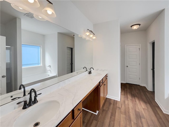 bathroom with a sink, visible vents, wood finished floors, and double vanity