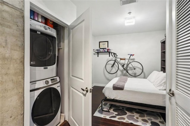 clothes washing area with stacked washer and clothes dryer and wood finished floors