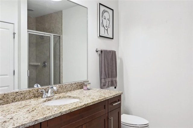 bathroom with a shower stall, vanity, and toilet