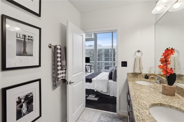 bathroom with double vanity, connected bathroom, and baseboards