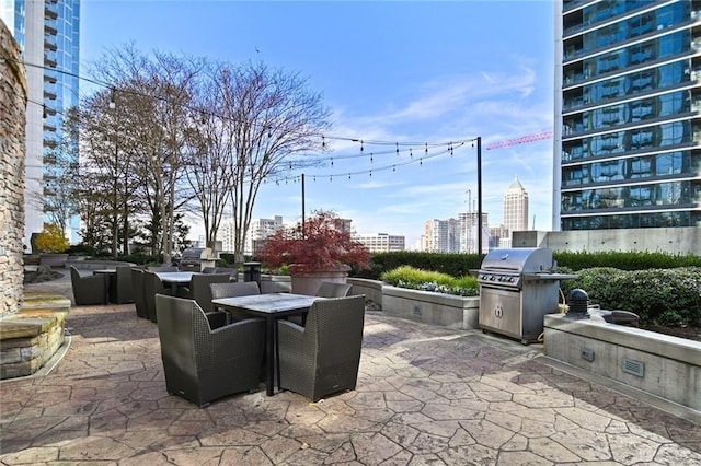 view of patio / terrace with outdoor dining space, a city view, and a grill