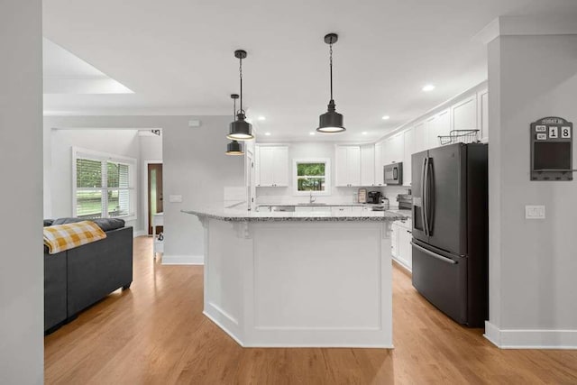 kitchen with a wealth of natural light, light wood-type flooring, white cabinets, and stainless steel appliances