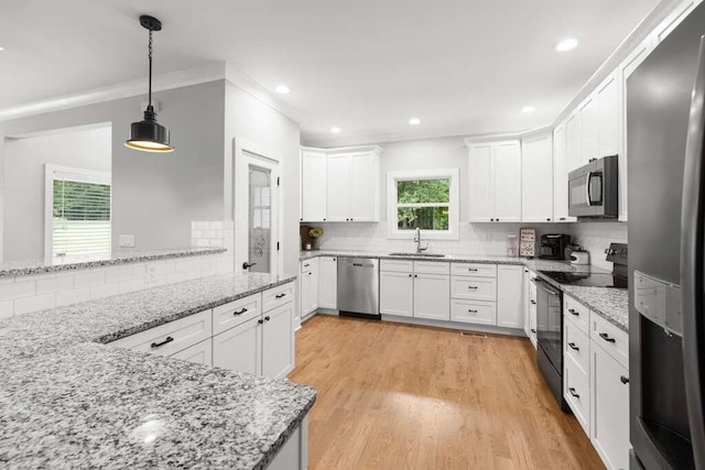 kitchen with stainless steel appliances, white cabinets, sink, tasteful backsplash, and light hardwood / wood-style flooring