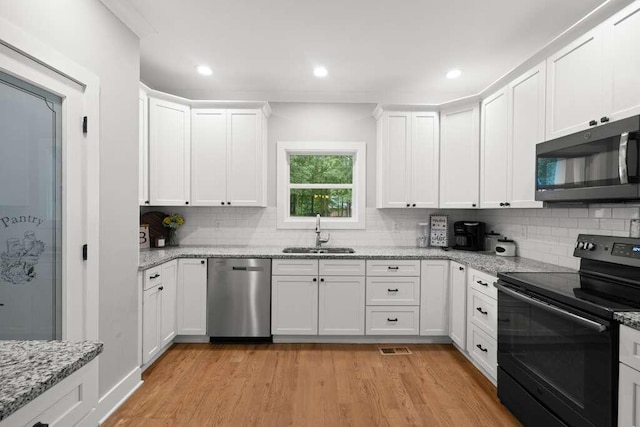 kitchen with white cabinets, sink, light hardwood / wood-style floors, and stainless steel appliances