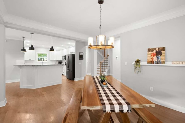 unfurnished dining area with a chandelier, ornamental molding, and light hardwood / wood-style flooring