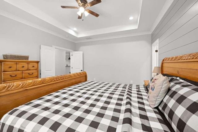 bedroom featuring wood walls, ceiling fan, and a tray ceiling