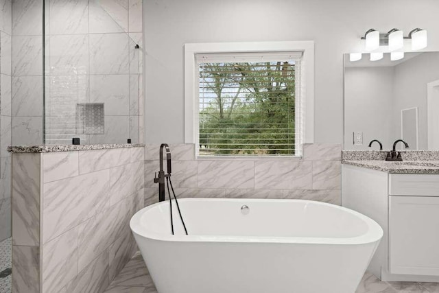 bathroom featuring a tub, vanity, and tile walls