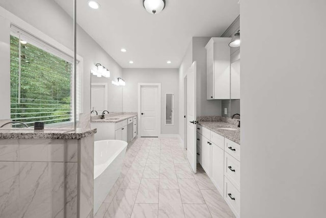 bathroom with vanity and tiled bath