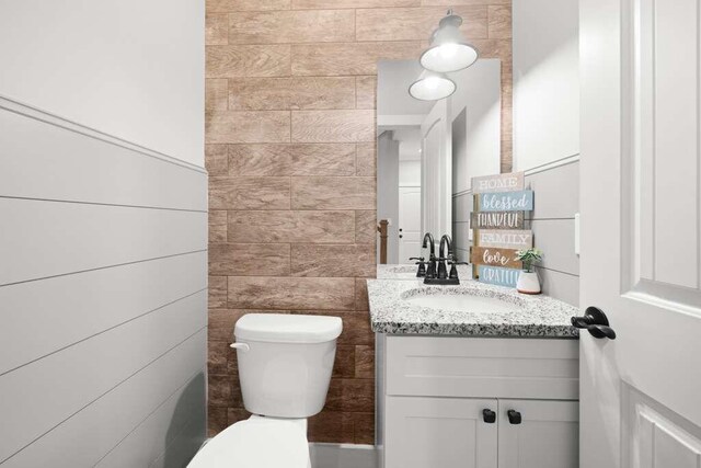 bathroom featuring vanity, toilet, and tile walls