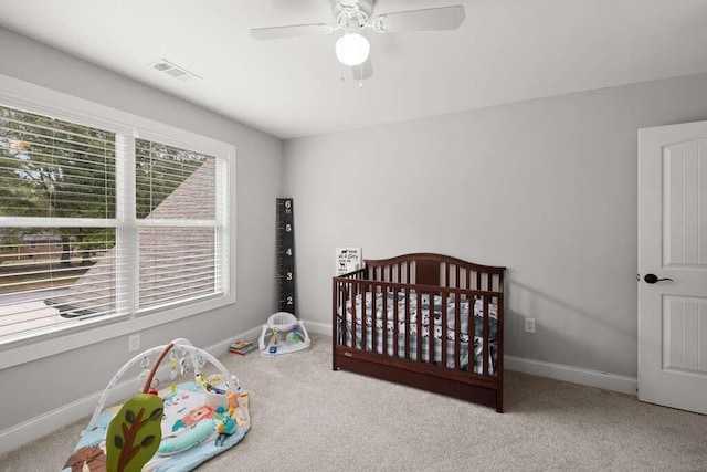 bedroom featuring ceiling fan, light carpet, and a nursery area