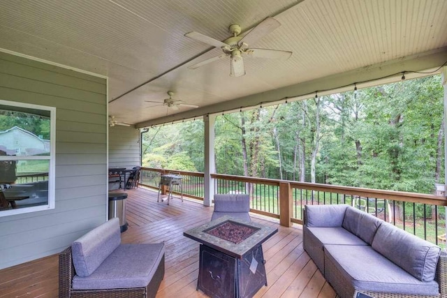 deck with ceiling fan and an outdoor living space with a fire pit