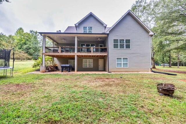 back of property featuring a patio, a yard, a trampoline, and an outdoor fire pit