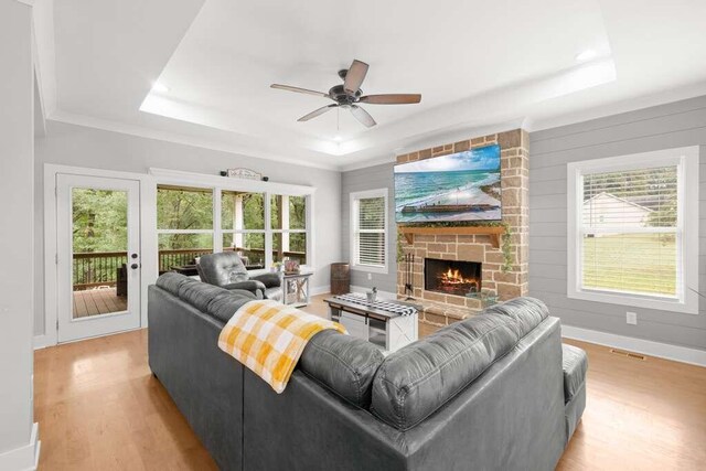 living room with a wealth of natural light, light hardwood / wood-style floors, and a raised ceiling