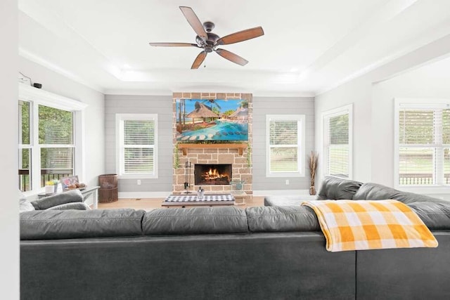 living room featuring a stone fireplace, wood-type flooring, ceiling fan, and a raised ceiling