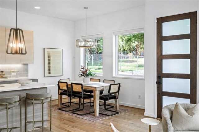 dining area with an inviting chandelier, baseboards, recessed lighting, and light wood finished floors